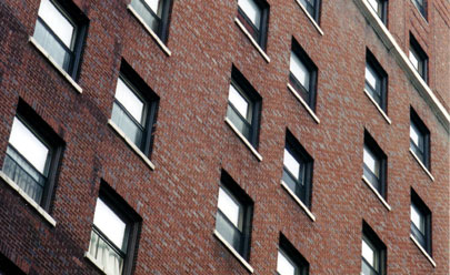 [photo of many open windows on the side of brick apartment building]